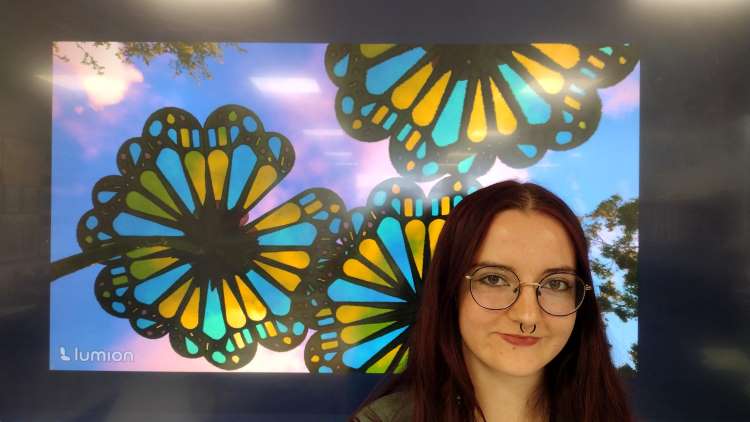 Photo shows student Lola Elmer posing with her artwork.