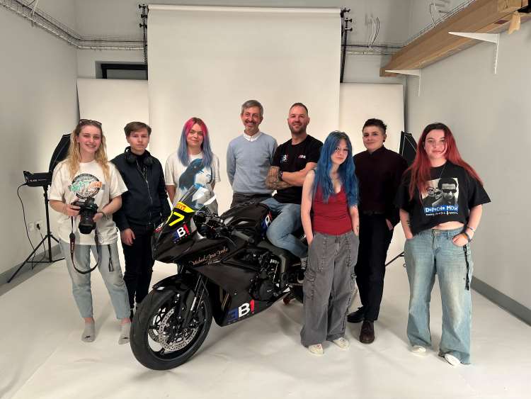 Photo shows Northampton College staff and students posing in the College photography studio with motorcyclist Alex Mann and his bike.