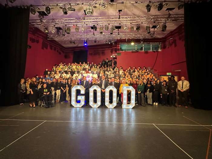 Staff and students pose behind large letters spelling 'GOOD'.