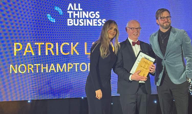 Patrick Leavey poses on stage with his award, joined by ceremony host Iain Stirling.