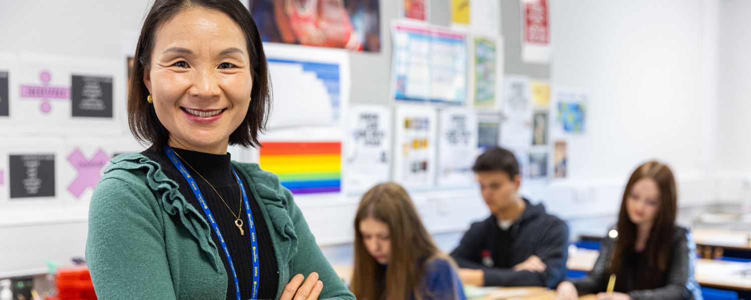 Female teacher poses to camera in a classroom