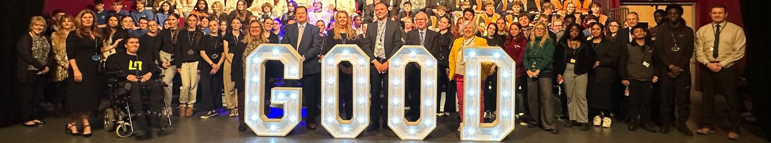 Staff and students pose behind large letters spelling 'GOOD'.