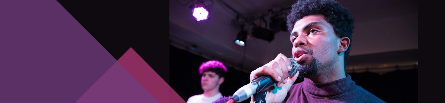 Male student singing into a microphone at our performance venue.